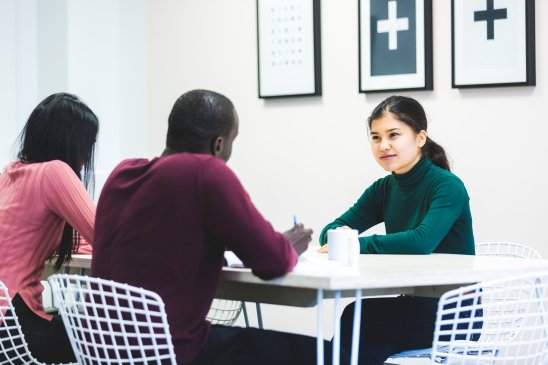 three people sitting around a table in a group discussion
